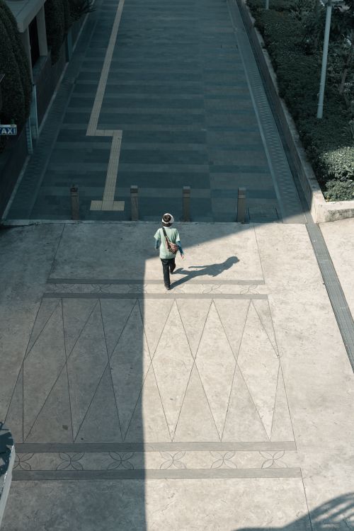 Free Top view of a person walking through a shadowed street in an urban setting. Stock Photo