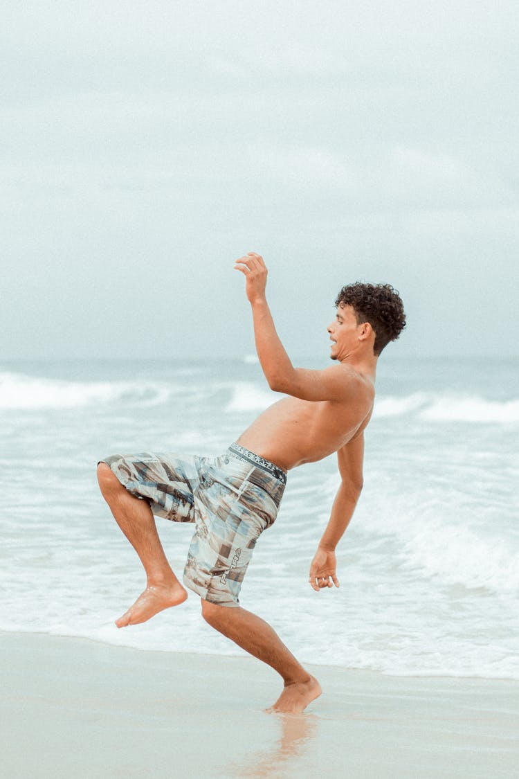 Man Standing On One Leg On Beach