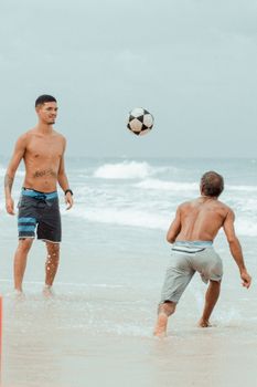 Shirtless men playing soccer at Canoa Quebrada Beach, Brazil, enjoying a lively seaside game.