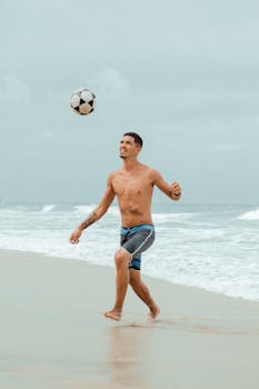 A shirtless man playing soccer on Canoa Quebrada beach, capturing a moment of leisure and fun.