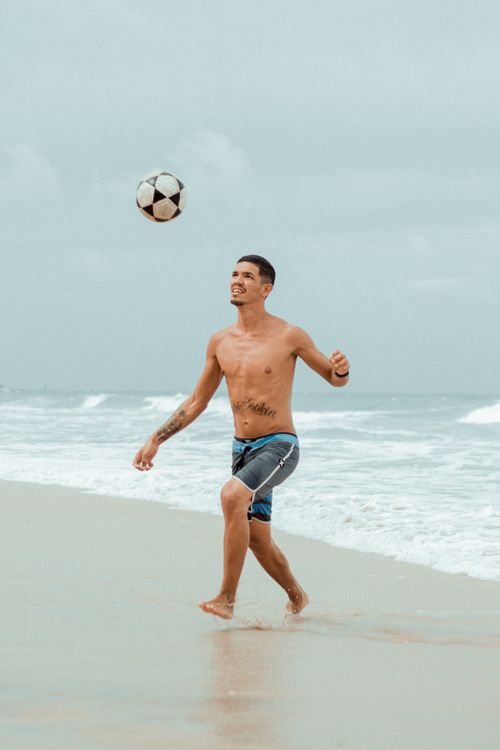 Free A shirtless man playing soccer on Canoa Quebrada beach, capturing a moment of leisure and fun. Stock Photo