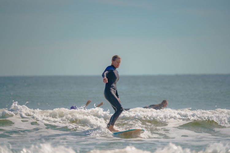 Woman In A Black And Blue Wetsuit Surfing