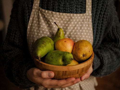 Free Close-up of a person holding a wooden bowl with fresh fruits including pears. Stock Photo