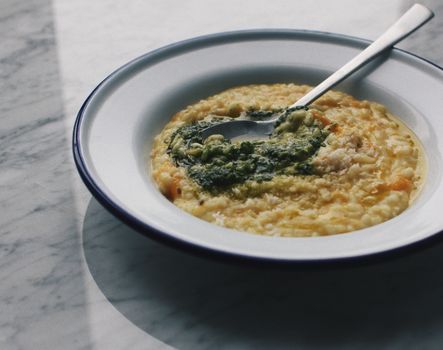 Delicious bowl of creamy risotto topped with pesto sauce, ideal for food photography.