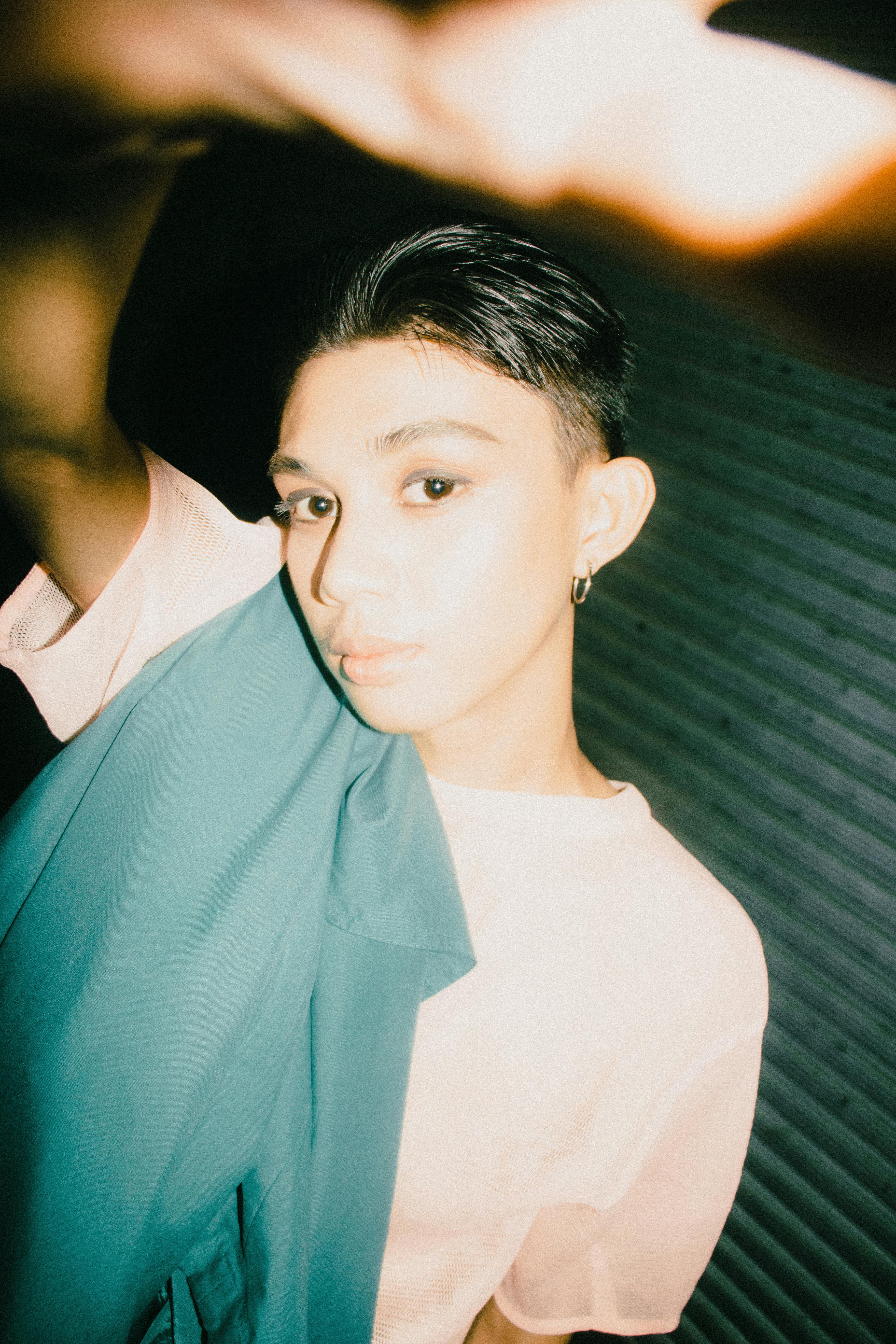 Dynamic close-up portrait depicting a stylish young Asian individual, capturing modern fashion and confidence.