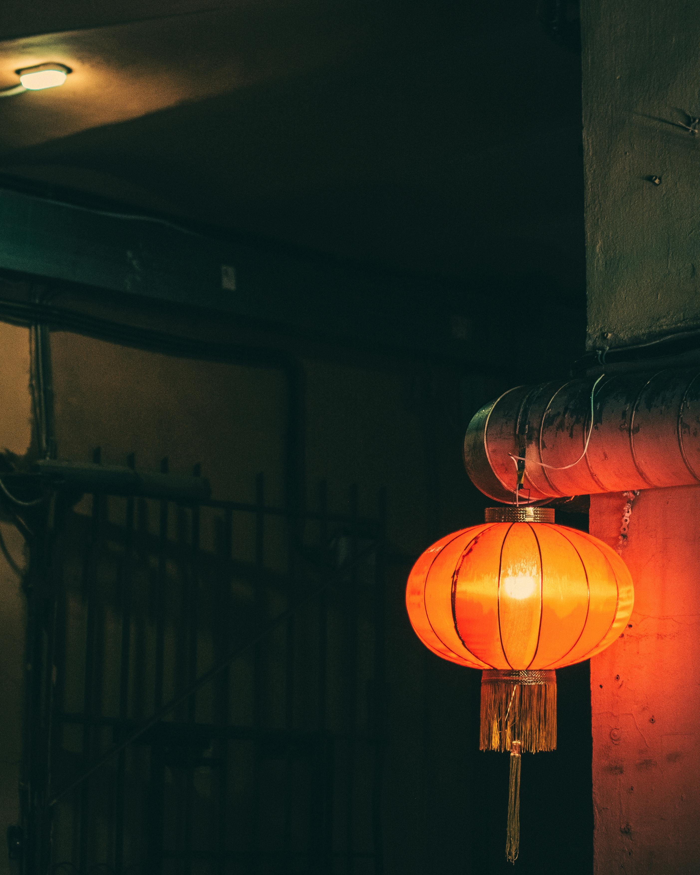 A red lantern casts a warm glow in a moody indoor setting. Perfect for atmospheric themes.