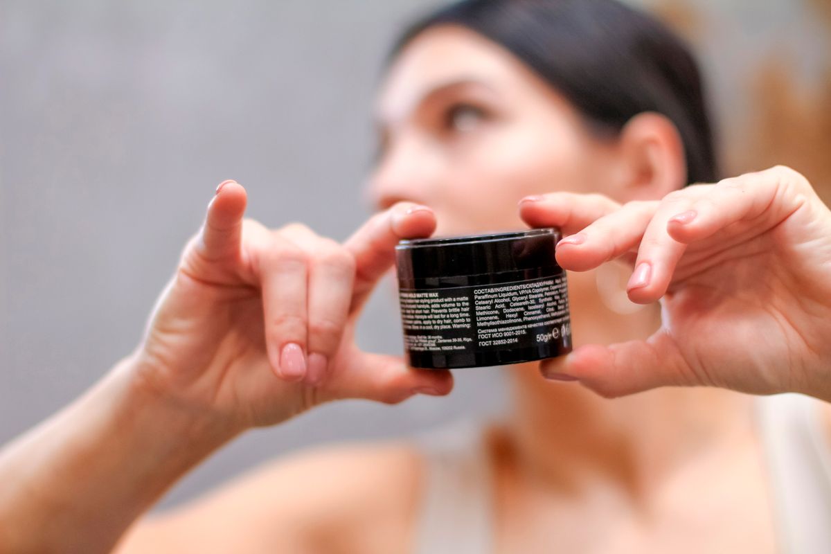 Woman holding and reading the label on a skincare product