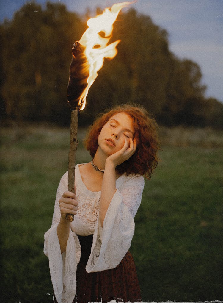 Portrait Of Woman With Eyes Closed Holding Lit Torch