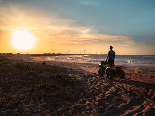 A Man Riding Atv on Beach during Sunset
