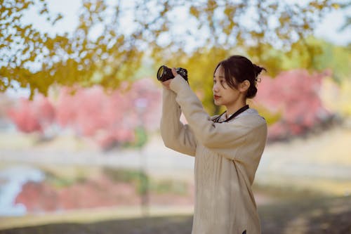 Woman in a Brown Sweater Using a Camera