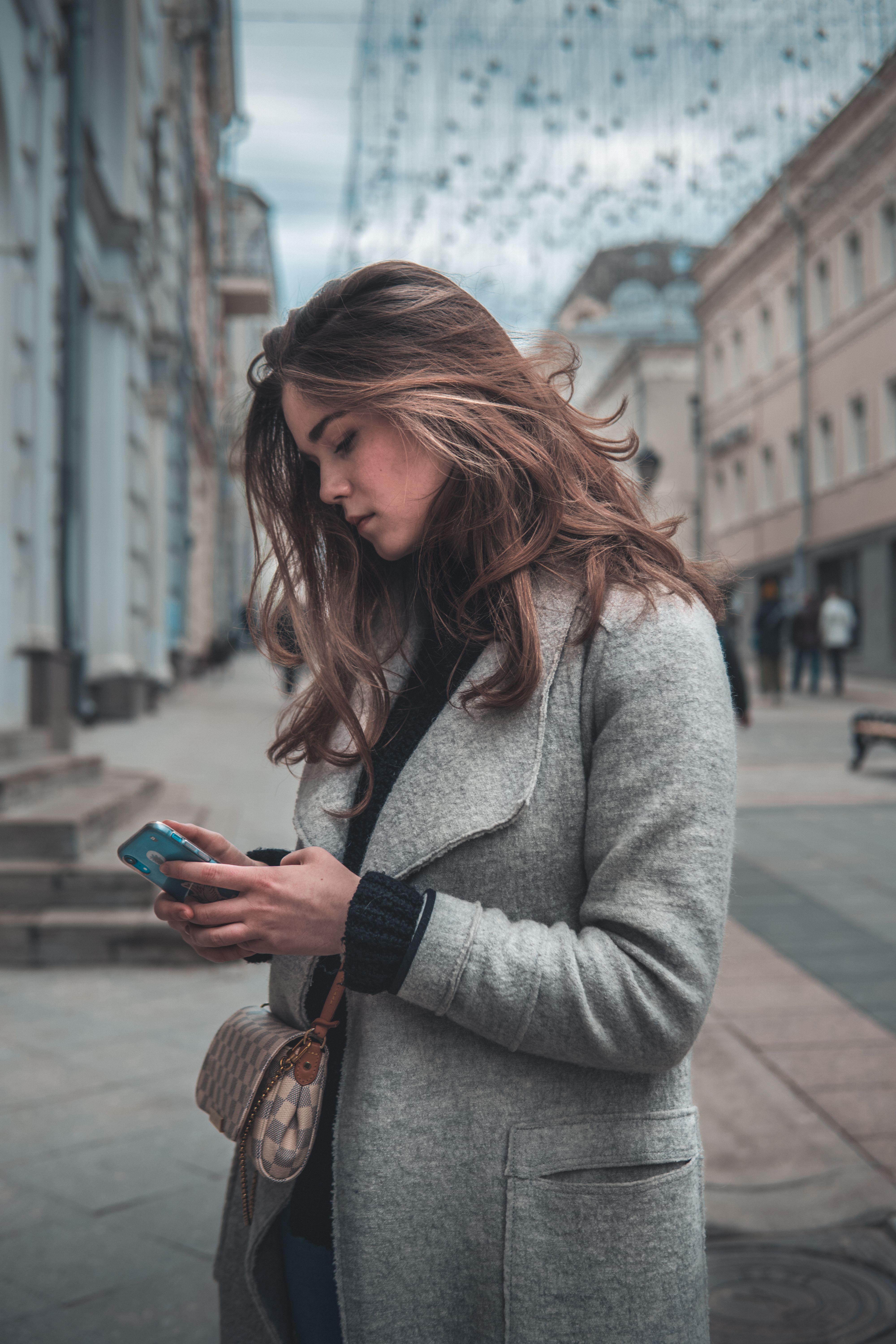 Woman in Gray Coat Holding a Smartphone · Free Stock Photo