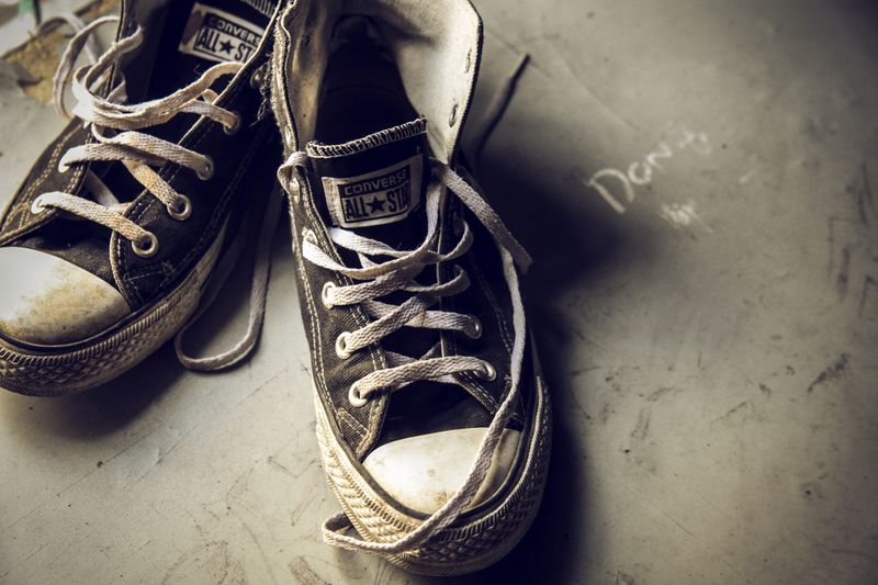 Close-up of worn Converse All Star sneakers, capturing a vintage and retro vibe on a muted background.