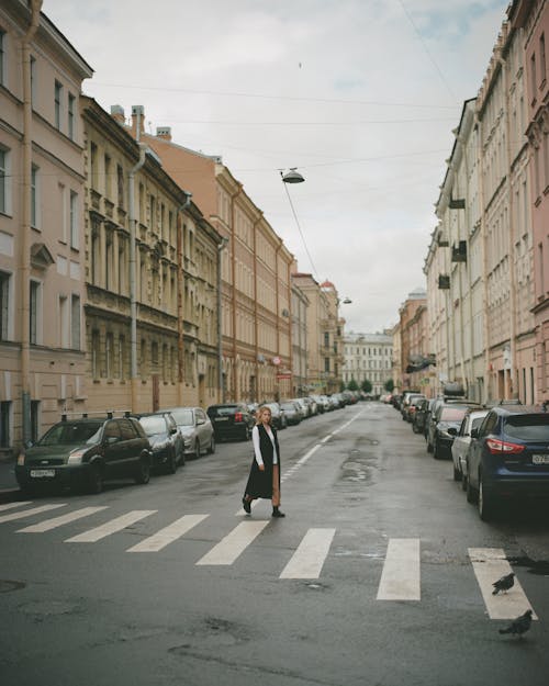 Photo of a Woman Crossing a Road with Cars 