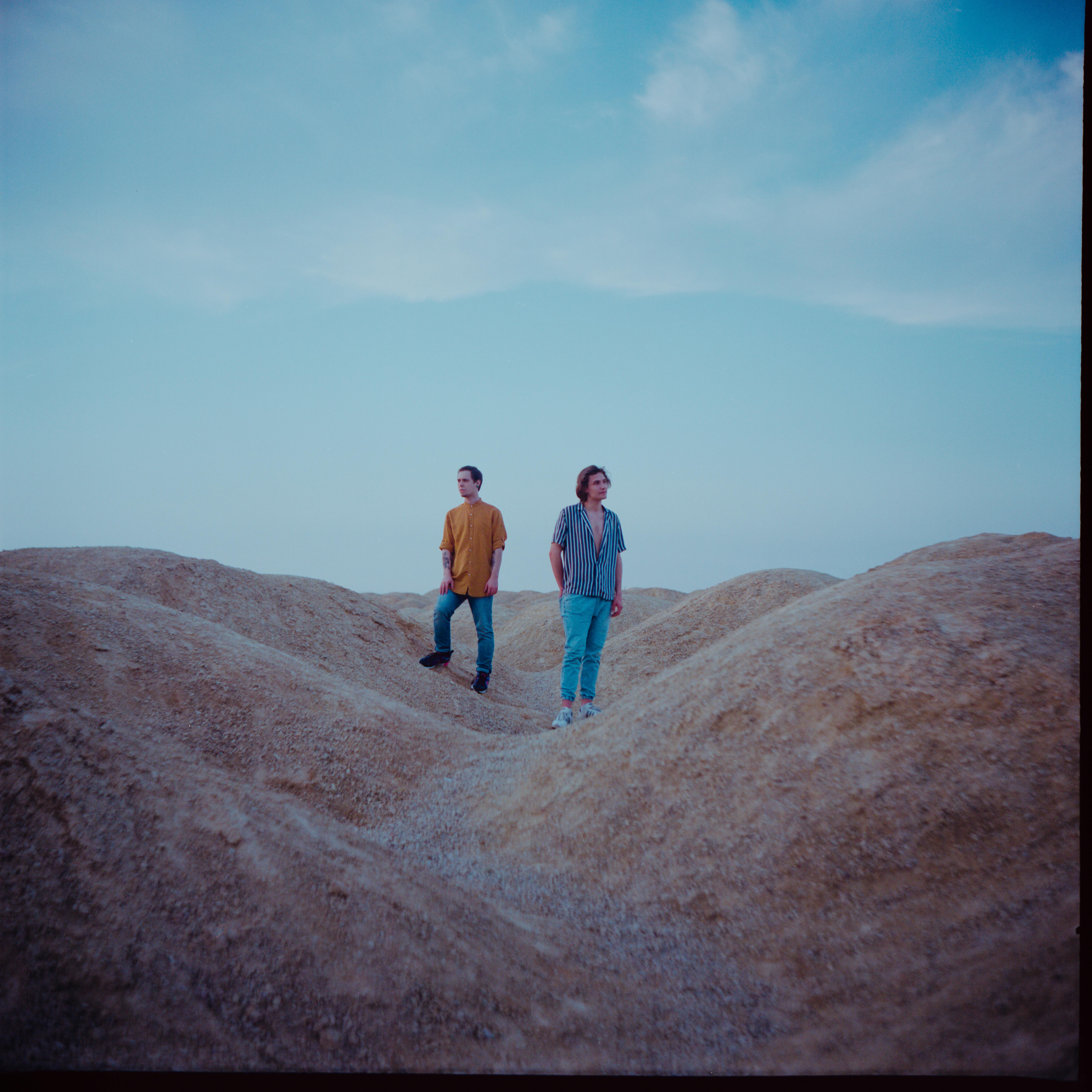 Two Men Standing on Brown Hills