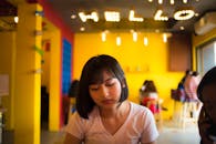 在越南一家色彩缤纷、氛围温馨的咖啡馆里，坐着一位亚洲女孩