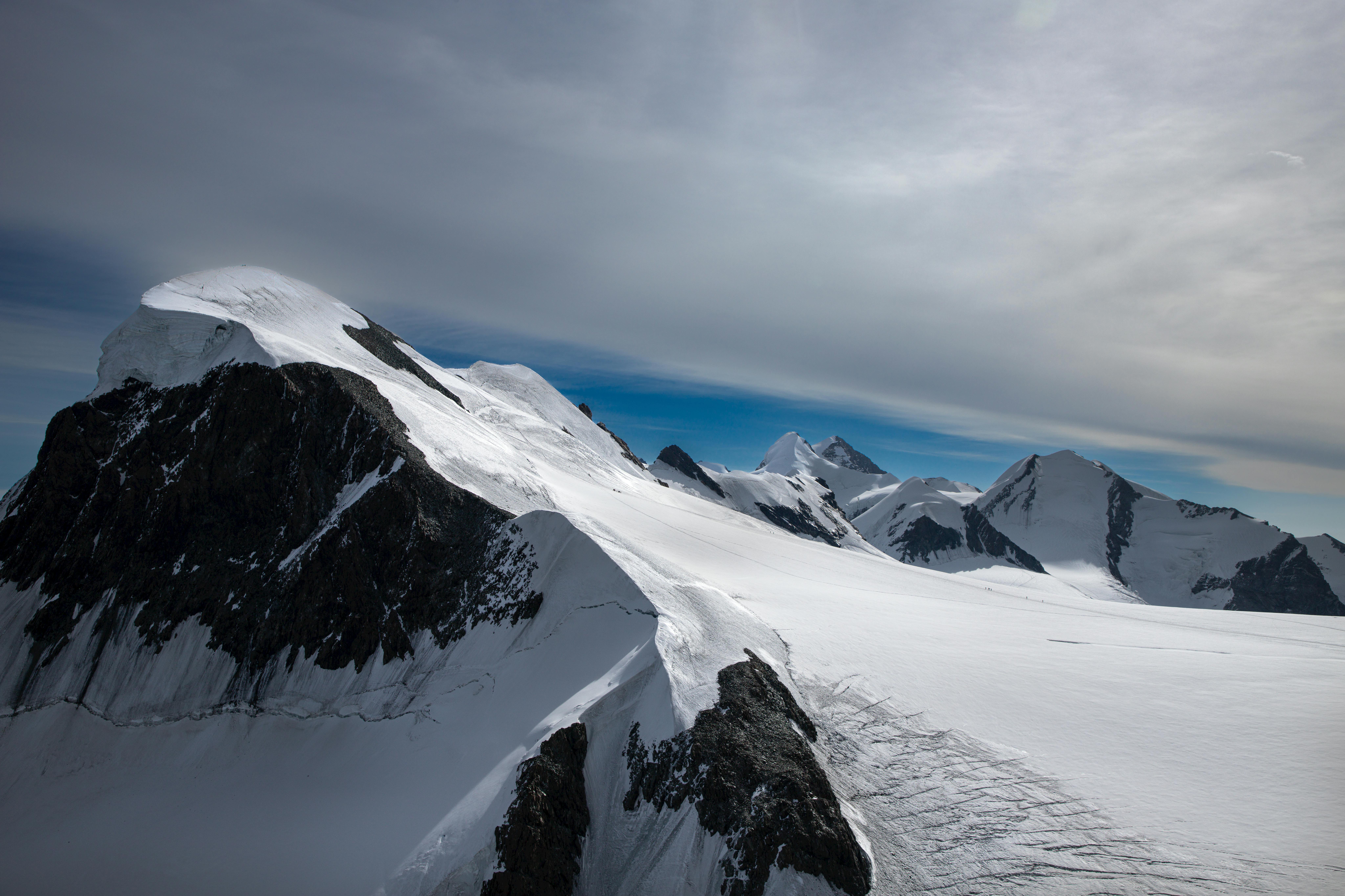 Majestic snow-covered peaks of Zermatt under a cloudy sky, epitomizing alpine beauty.