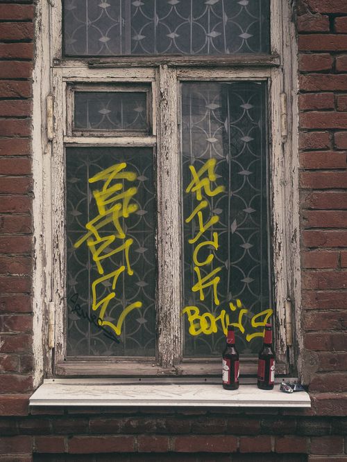 Free Close-up of a vintage window with graffiti on a weathered brick wall, two bottles on the sill. Stock Photo