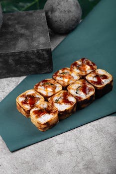 Delicious Japanese sushi rolls with sauce displayed on a stylish stone table setting.