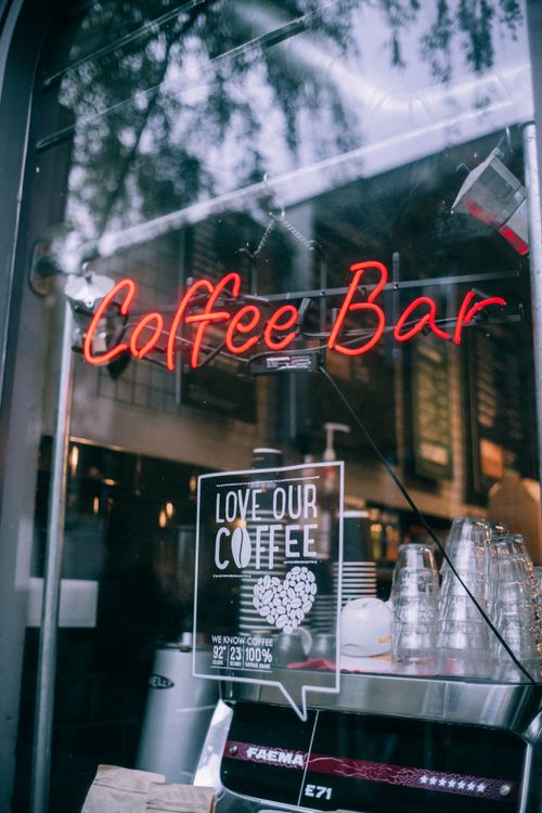 Free Stylish coffee bar with neon sign, glassware, and urban reflections. Stock Photo