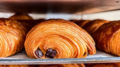 Free Delicious close-up of a golden, freshly baked chocolate croissant on display. Stock Photo
