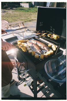 Grilled fish and corn on an outdoor barbecue in a summer setting.