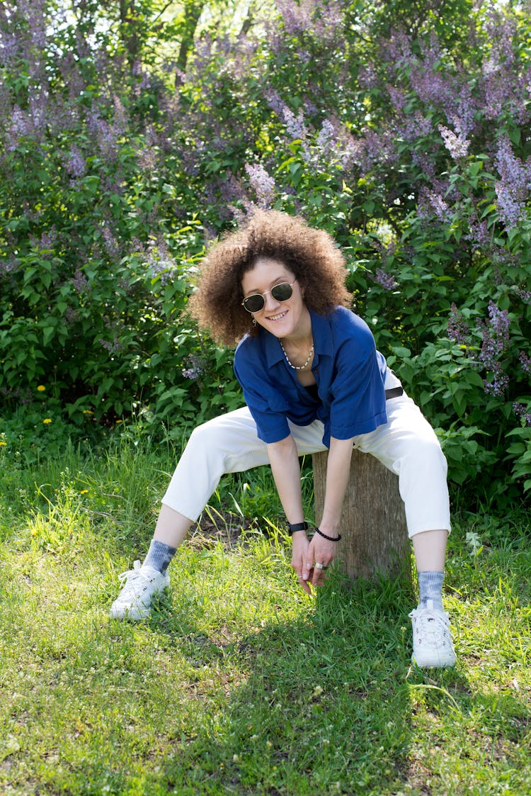 A Woman Sitting On A Log Bending Forward