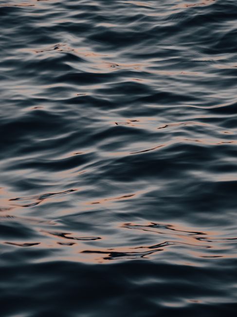 A serene view of ocean waves with a gentle sunset reflection.