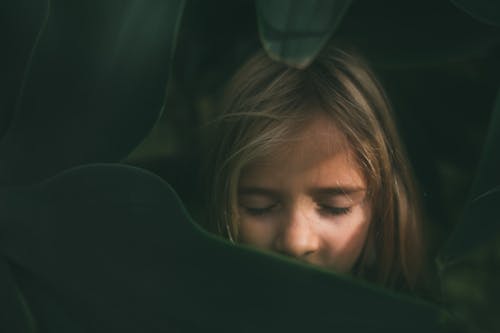 Free Photo of a Girl Closing Her Eyes Near Green Leaves Stock Photo