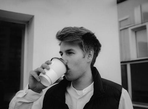 Grayscale Photo of a Man Drinking Coffee