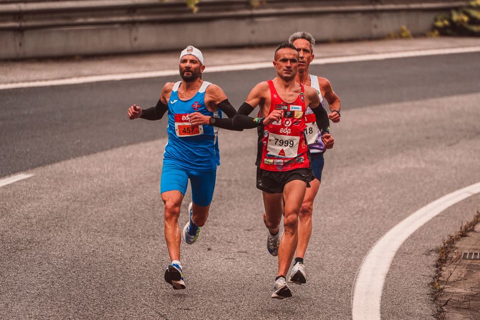 Three male runners competing in a marathon on a city road. Capturing endurance and athleticism.