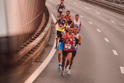 A group of male athletes competing in a city marathon, featuring diverse runners and dynamic movement.