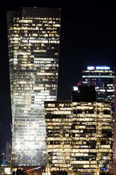 A vibrant skyline featuring illuminated modern skyscrapers in the evening.
