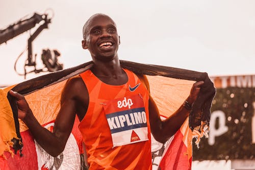 Free Smiling Man in Orange Jersey Holding a Banner Stock Photo