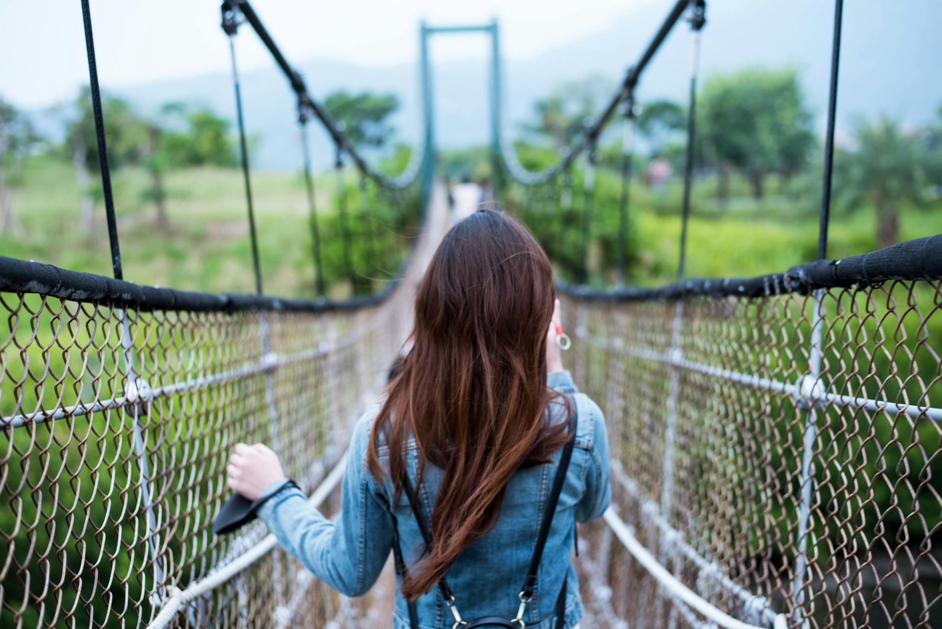 Woman in Blue Long-sleeved Dress on Rope Bridge