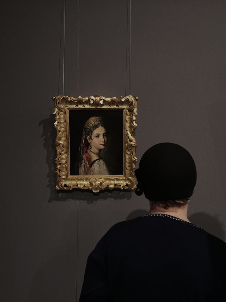 Back View Of A Man Looking At Painting In A Museum 