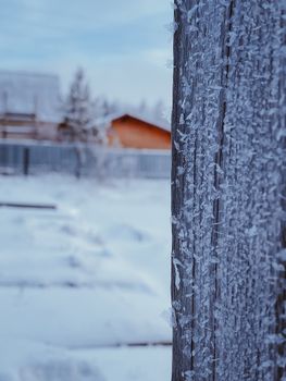 Close-up of frosted wooden fence, snowy landscape in winter.
