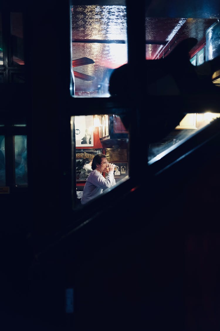 Man Sitting In A Pub Photographed From The Outside 