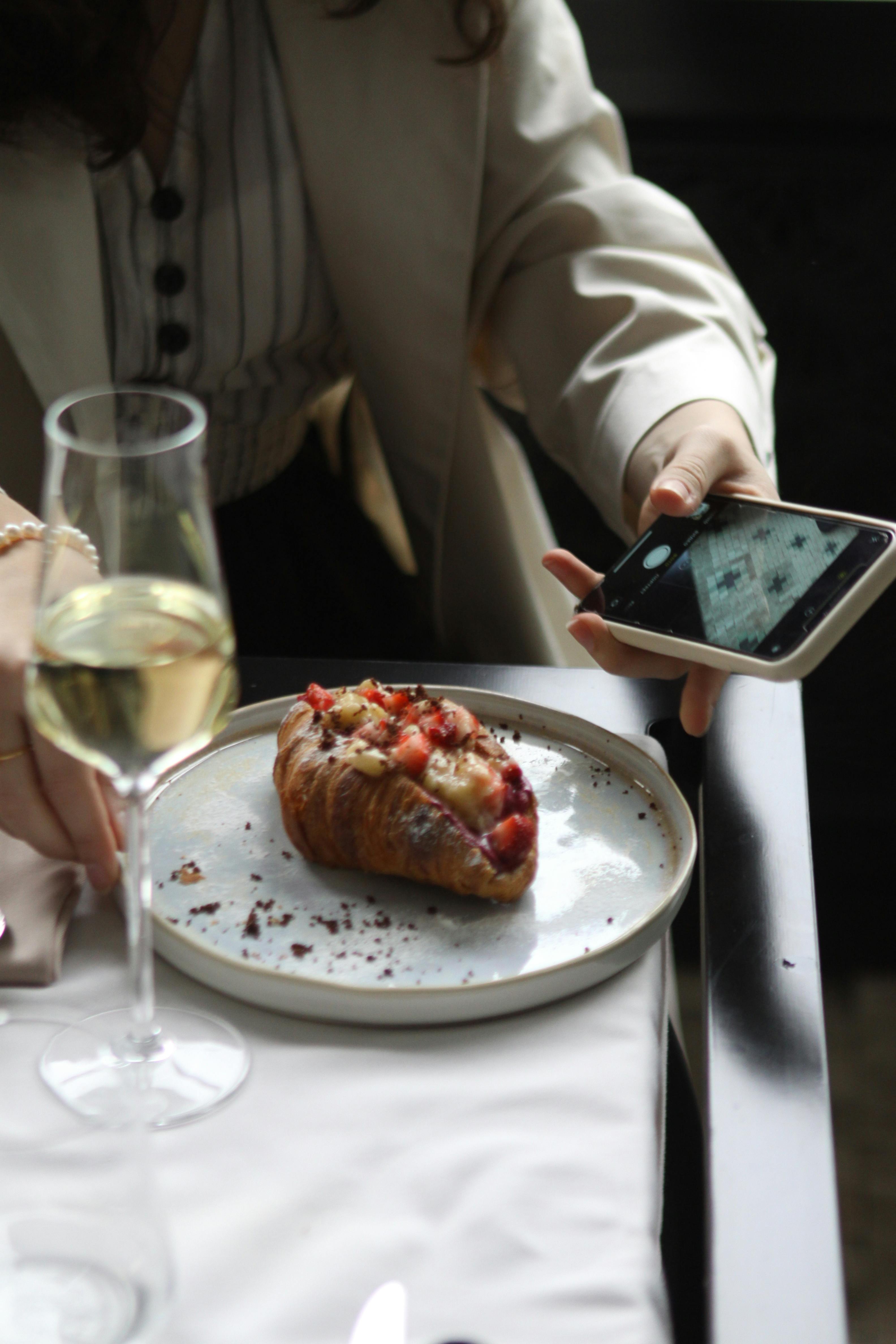 Stylish brunch setting with a strawberry croissant and a glass of white wine.