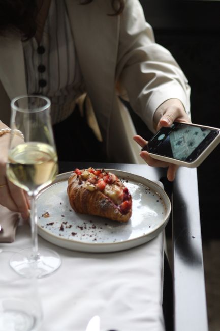Stylish brunch setting with a strawberry croissant and a glass of white wine.