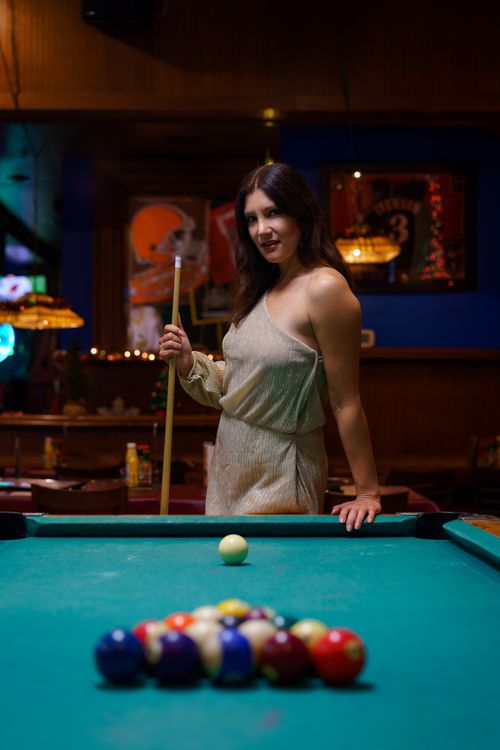 Free Chic woman in a dress playing pool at an Orlando bar, showcasing style and leisure. Stock Photo