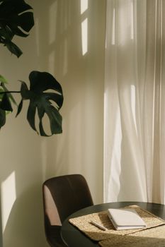 A warm, inviting home interior featuring a sunlit table with a monstera plant casting a shadow.
