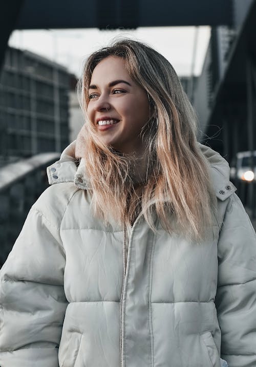 Free Portrait of a Woman in a Jacket Looking Away while Smiling Stock Photo