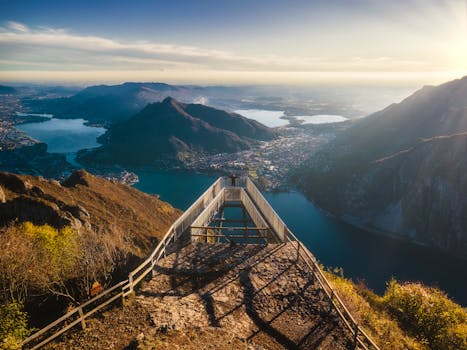 A stunning aerial shot of a view deck overlooking mountains and lakes at sunset.