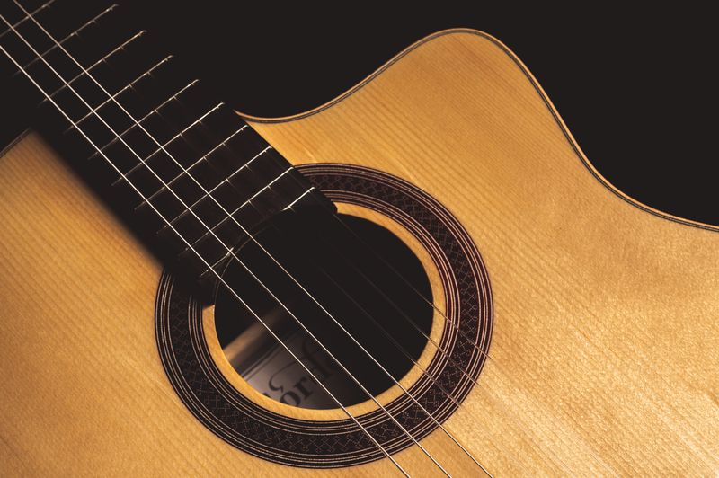 Gros plan du corps d'une guitare acoustique montrant les cordes et la rosace — inspection détaillée