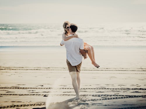 Photo of a Man Carrying a Woman at the Beach