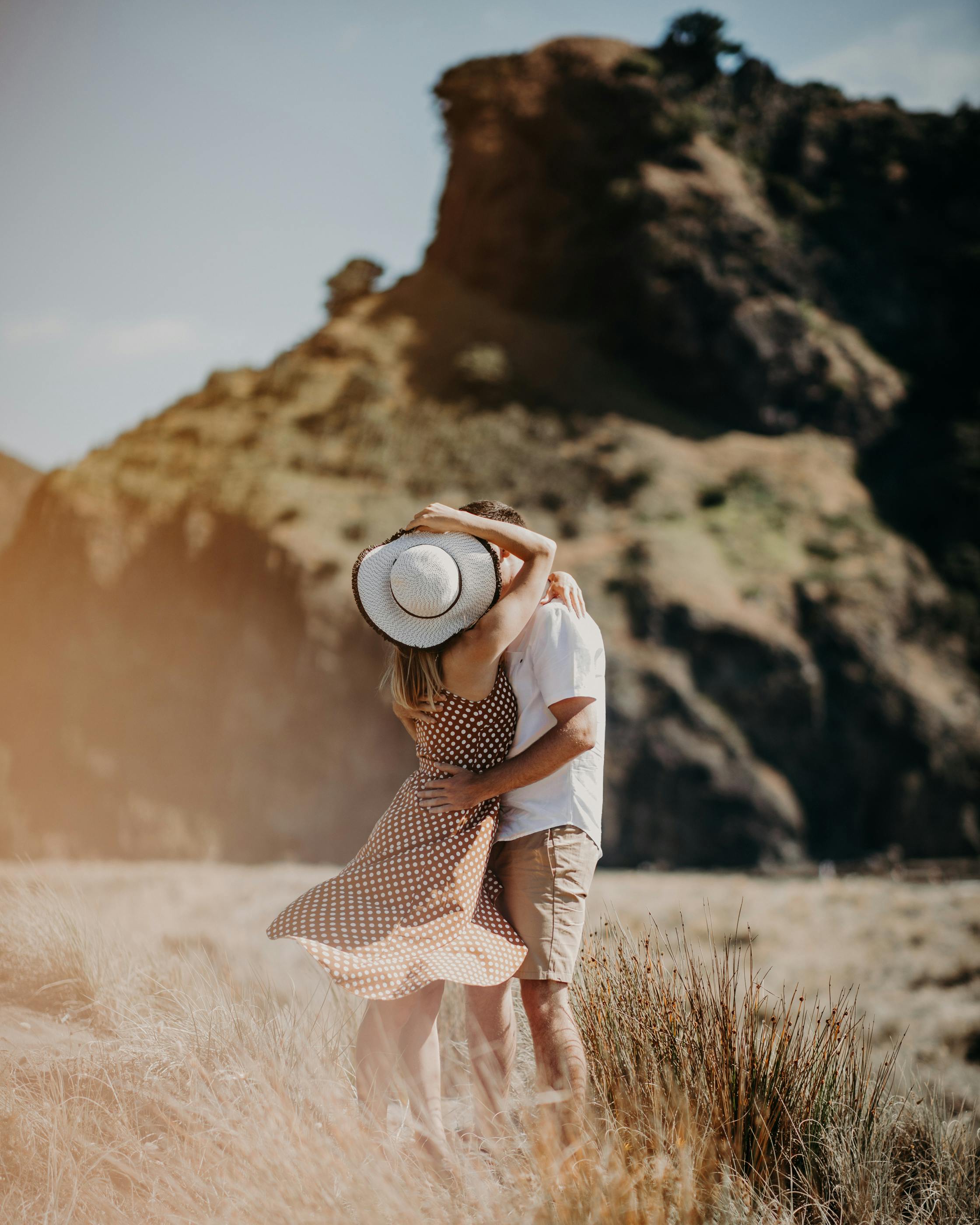 A romantic couple embracing in a sunny summer landscape with rock formations.