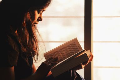 A reader lost in a book by the window
