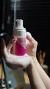 Person Holding White and Pink Plastic Bottle