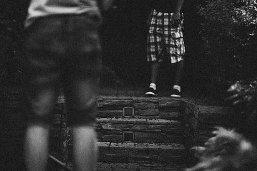Blurred black and white image focusing on footwear and steps outdoors.