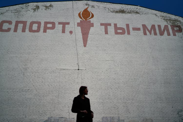 Woman Standing Against Wall With Sport Slogan